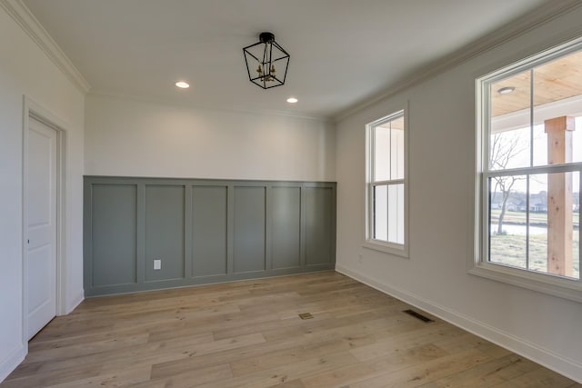 empty room with ornamental molding and light hardwood / wood-style floors