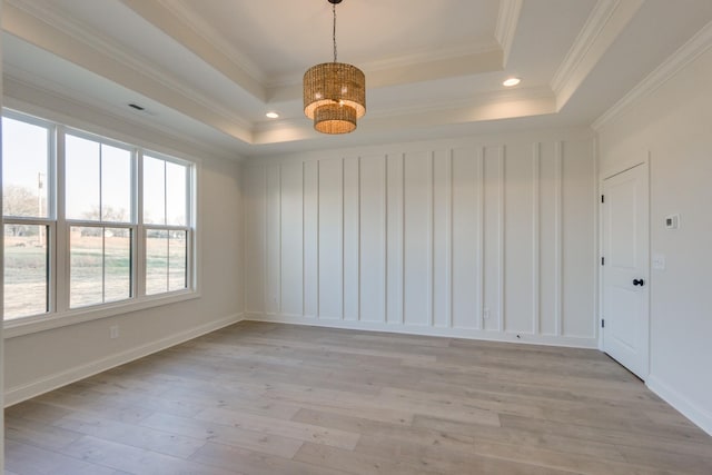 unfurnished room featuring crown molding, a raised ceiling, and light wood-type flooring