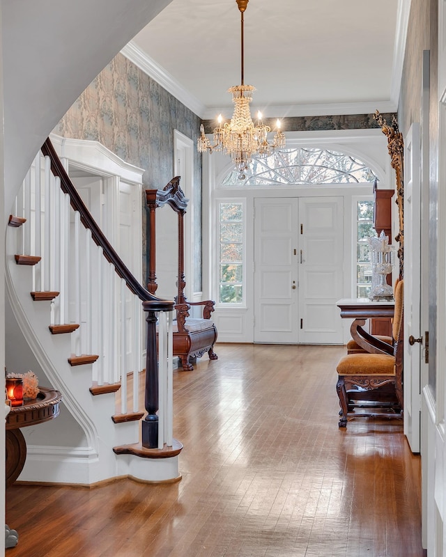 entryway featuring hardwood / wood-style flooring, ornamental molding, and a notable chandelier