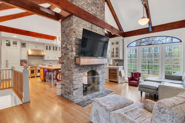 living room featuring wine cooler, beam ceiling, light hardwood / wood-style flooring, and high vaulted ceiling