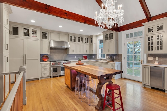 kitchen with pendant lighting, sink, wooden counters, beam ceiling, and range with two ovens