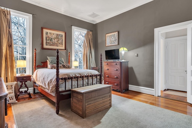 bedroom featuring multiple windows, crown molding, and light hardwood / wood-style flooring