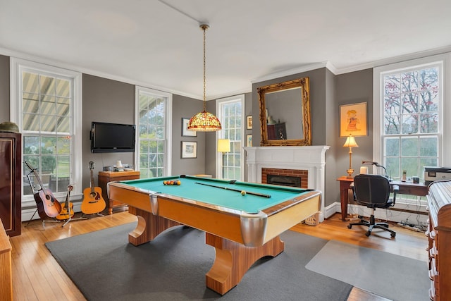 rec room featuring ornamental molding, a brick fireplace, pool table, and light hardwood / wood-style floors