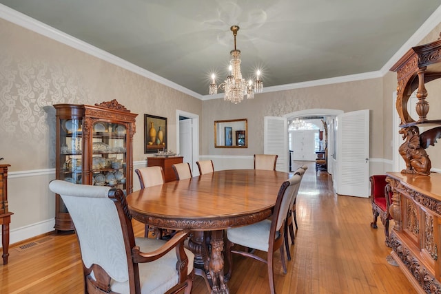 dining space featuring an inviting chandelier, light hardwood / wood-style flooring, and ornamental molding