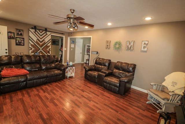 living room featuring ceiling fan, a barn door, and dark hardwood / wood-style flooring