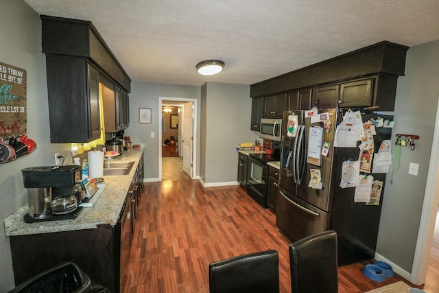 kitchen featuring light stone countertops, appliances with stainless steel finishes, dark hardwood / wood-style floors, and a textured ceiling