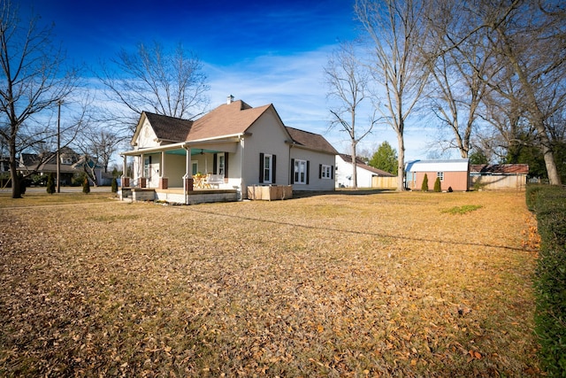 view of home's exterior with a porch, a yard, and a storage shed