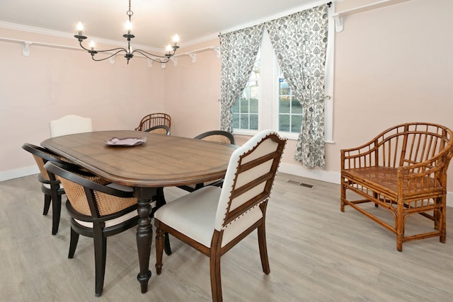 dining area with light hardwood / wood-style flooring, ornamental molding, and a chandelier