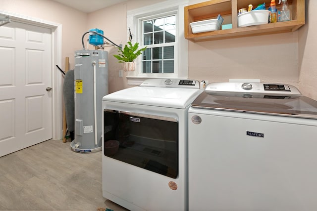 washroom with washer and dryer, light hardwood / wood-style floors, and electric water heater