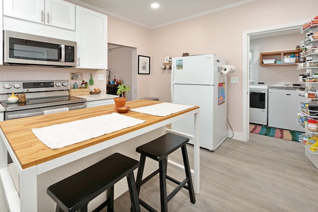 kitchen with a breakfast bar, white cabinetry, ornamental molding, independent washer and dryer, and stainless steel appliances