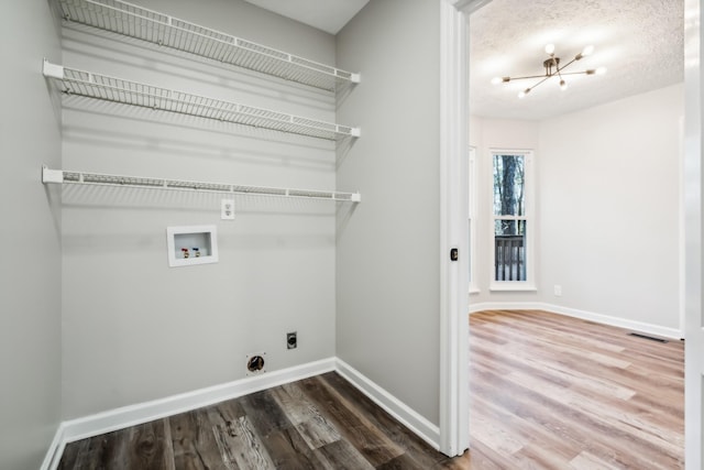 clothes washing area with hardwood / wood-style flooring, an inviting chandelier, washer hookup, a textured ceiling, and hookup for an electric dryer