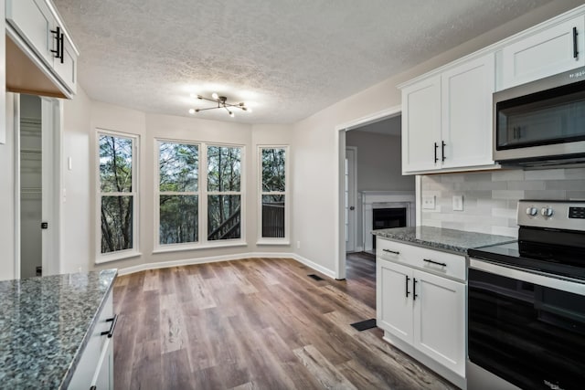 kitchen with tasteful backsplash, white cabinetry, appliances with stainless steel finishes, and dark stone countertops