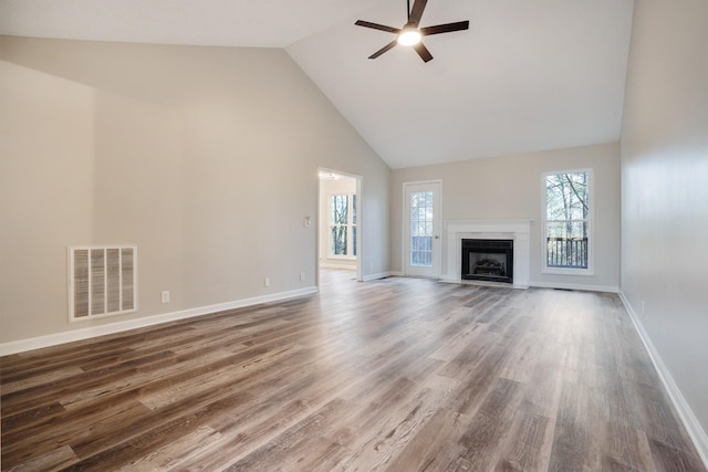 unfurnished living room with ceiling fan, high vaulted ceiling, dark hardwood / wood-style floors, and a healthy amount of sunlight