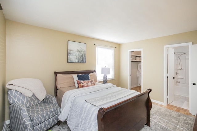 bedroom with ensuite bathroom, a spacious closet, and baseboards