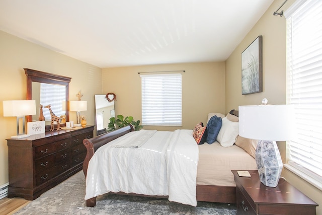 bedroom with hardwood / wood-style floors and a baseboard heating unit