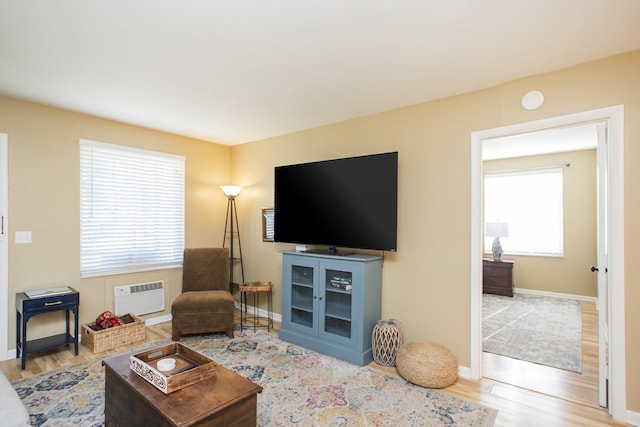 living area featuring a wall mounted AC, wood finished floors, and baseboards