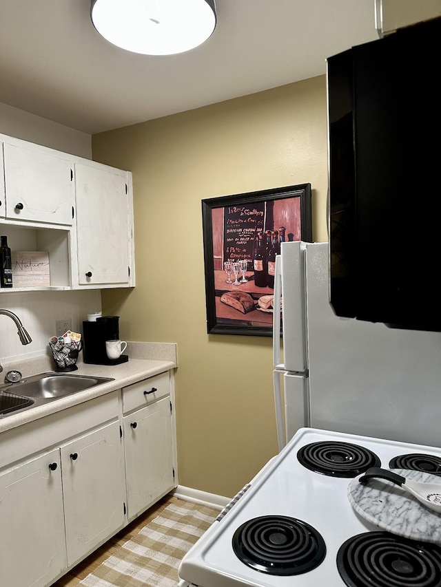 kitchen featuring light countertops, electric range, a sink, and white cabinetry