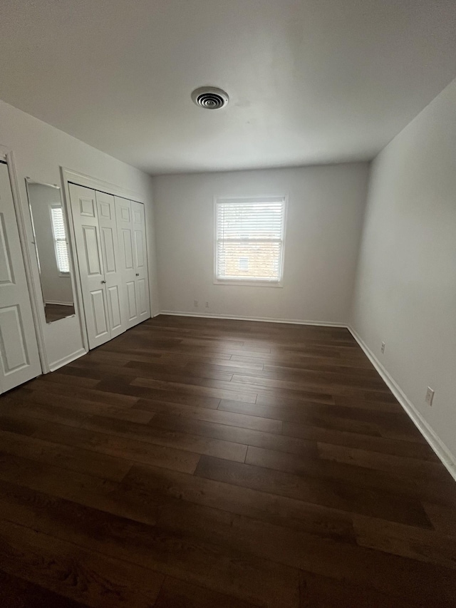 unfurnished bedroom featuring dark hardwood / wood-style floors and a closet