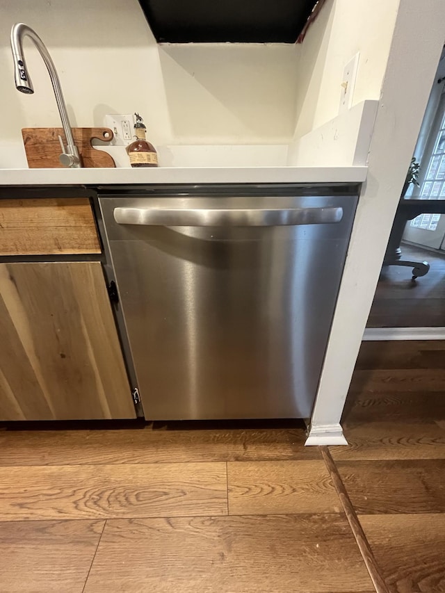 details with stainless steel dishwasher and hardwood / wood-style floors