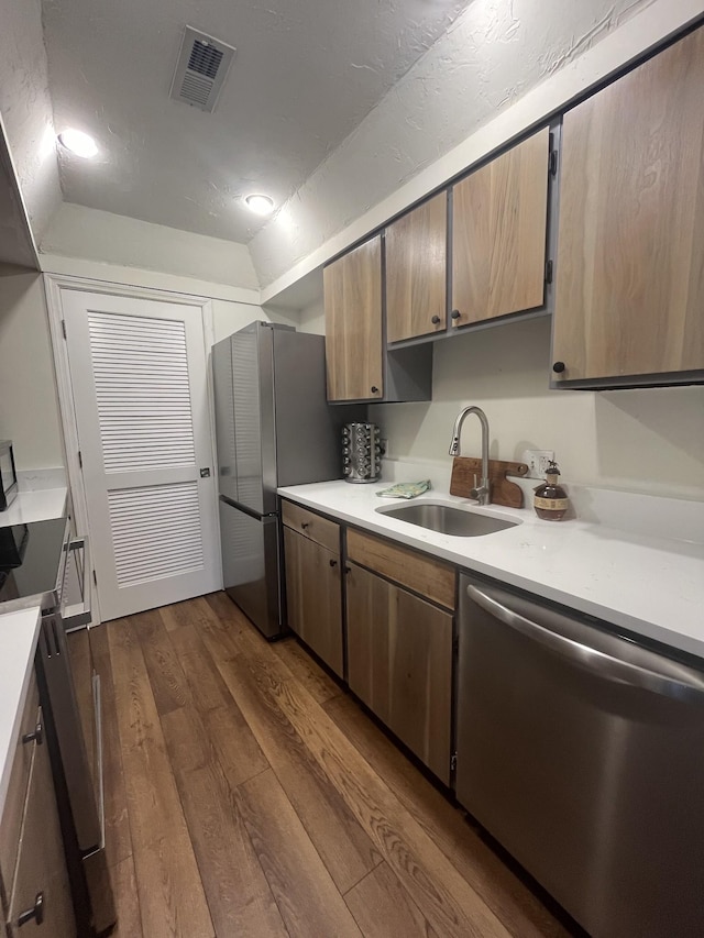 kitchen with appliances with stainless steel finishes, dark hardwood / wood-style floors, and sink