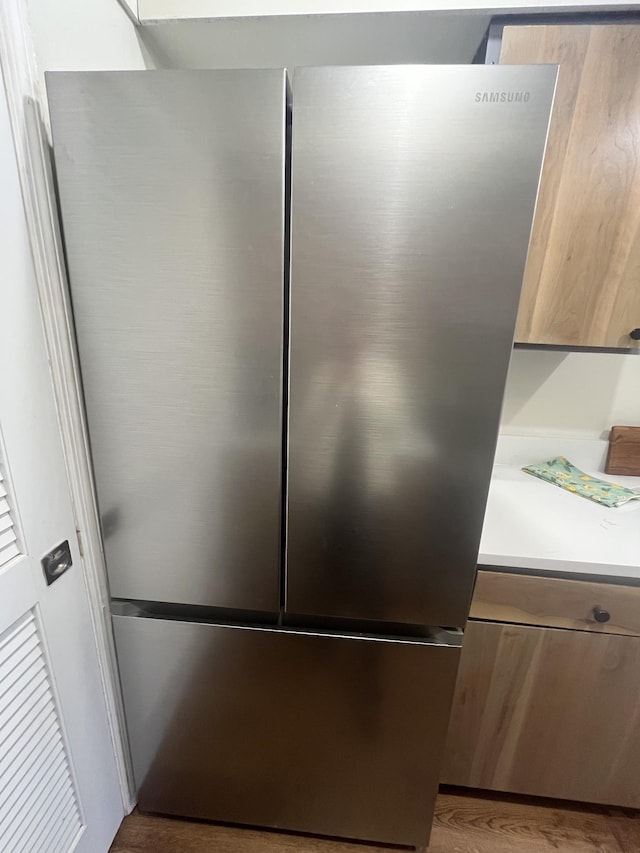 interior details with hardwood / wood-style flooring, stainless steel fridge, and light brown cabinetry