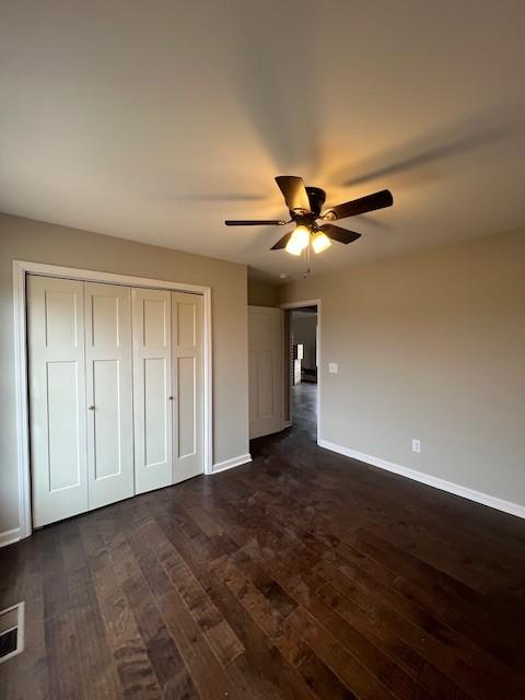 unfurnished bedroom with ceiling fan, dark hardwood / wood-style flooring, and a closet