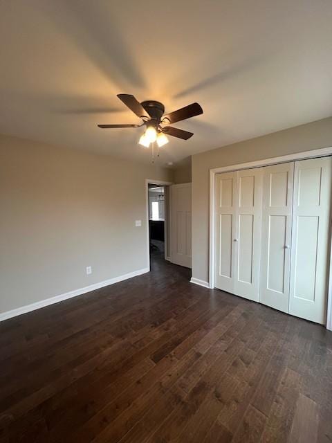 unfurnished bedroom with dark wood-type flooring, ceiling fan, and a closet