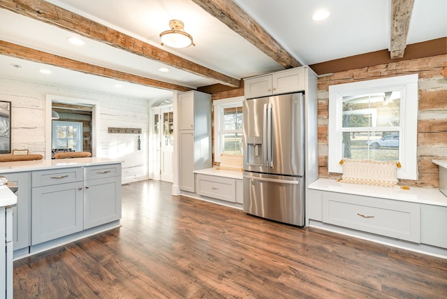 kitchen with dark wood-type flooring, stainless steel fridge, beam ceiling, and a wealth of natural light