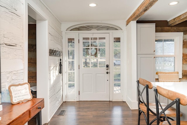 foyer featuring plenty of natural light, dark wood-type flooring, and beam ceiling