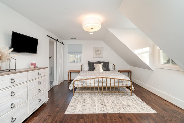 bedroom with vaulted ceiling, a barn door, and dark wood-type flooring