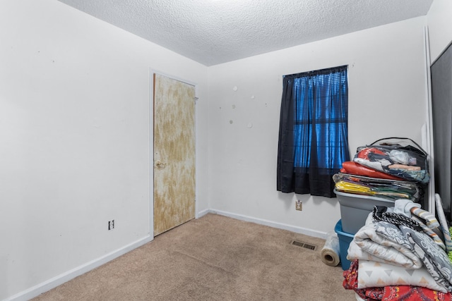 bedroom with carpet floors, visible vents, a textured ceiling, and baseboards