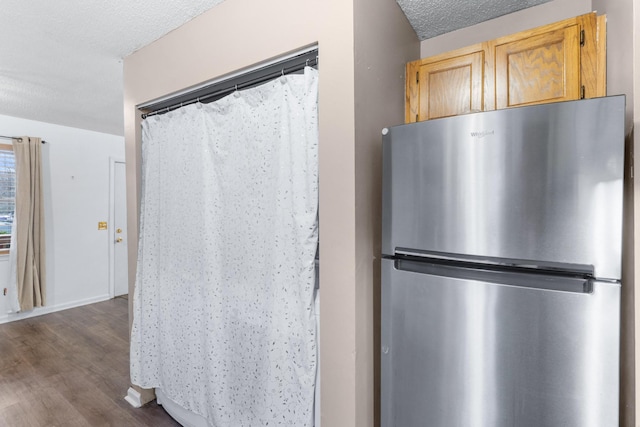 kitchen featuring a textured ceiling, dark wood-style flooring, and freestanding refrigerator