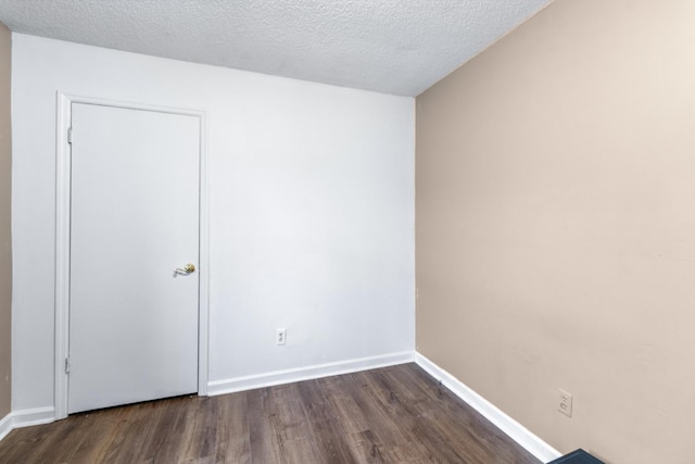 spare room with baseboards, dark wood finished floors, and a textured ceiling