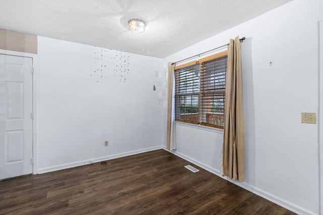 unfurnished room featuring visible vents, a textured ceiling, baseboards, and wood finished floors