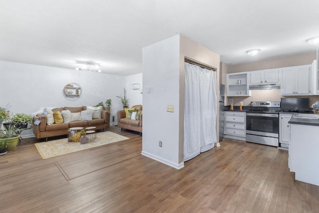 kitchen featuring electric range, dark countertops, open floor plan, wood finished floors, and under cabinet range hood