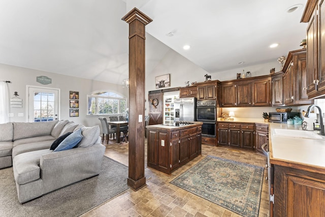 kitchen featuring ornate columns, sink, a center island, dark brown cabinetry, and black appliances