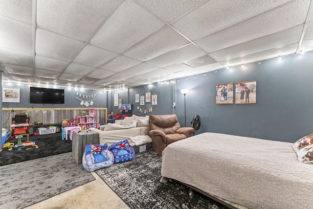 bedroom featuring a drop ceiling and concrete flooring