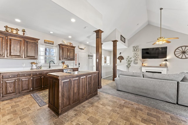 kitchen featuring dark brown cabinetry, sink, ornate columns, a center island, and dishwasher