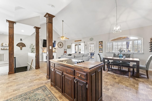 kitchen with dark brown cabinetry, high vaulted ceiling, a kitchen island, black electric stovetop, and decorative columns