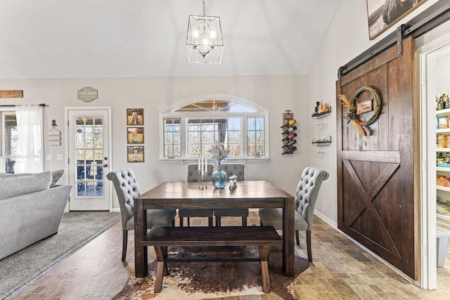 dining room with a barn door, lofted ceiling, and a chandelier