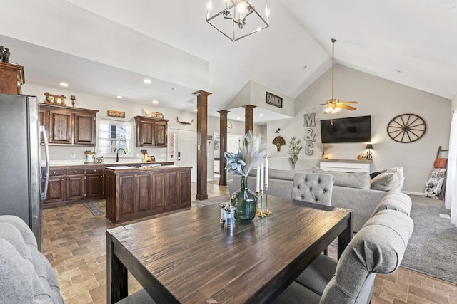 dining area with ceiling fan, high vaulted ceiling, sink, and decorative columns