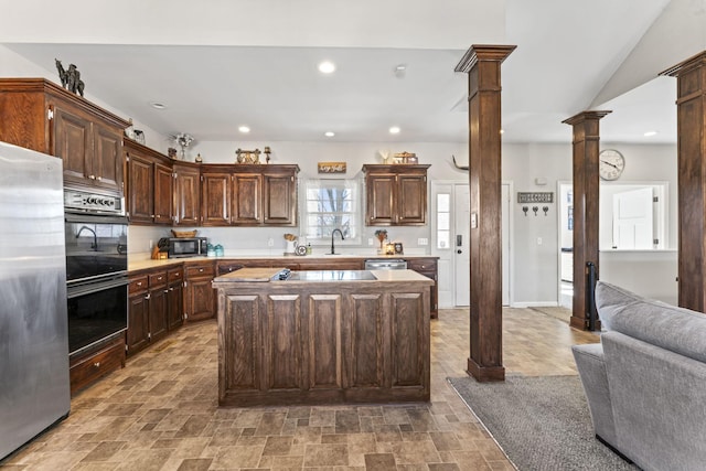 kitchen with decorative columns, a kitchen island, dark brown cabinets, and stainless steel appliances