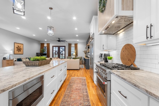 kitchen with pendant lighting, stainless steel appliances, light stone counters, and white cabinets