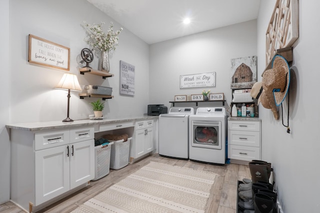 laundry area with cabinets, washing machine and clothes dryer, and light hardwood / wood-style flooring