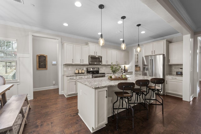 kitchen featuring white cabinetry, hanging light fixtures, an island with sink, and appliances with stainless steel finishes