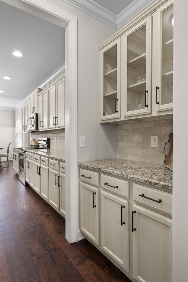 kitchen with dark hardwood / wood-style floors, tasteful backsplash, light stone counters, stainless steel appliances, and crown molding