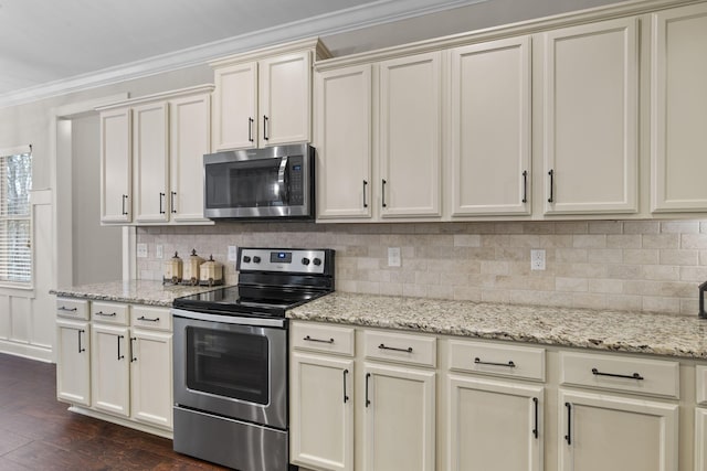 kitchen featuring crown molding, appliances with stainless steel finishes, light stone counters, decorative backsplash, and cream cabinetry