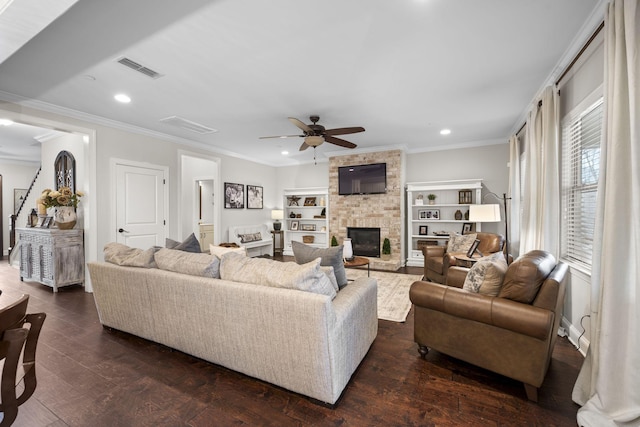 living room with crown molding, dark wood-type flooring, ceiling fan, and a fireplace