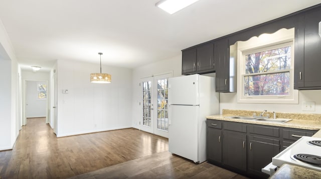 kitchen featuring sink, dark hardwood / wood-style flooring, hanging light fixtures, white appliances, and french doors