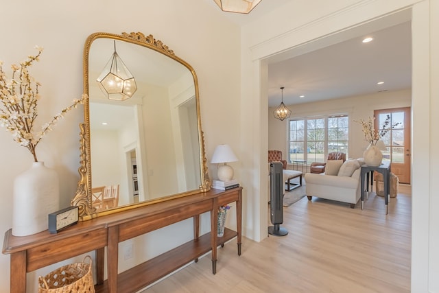 hall with an inviting chandelier and light hardwood / wood-style floors